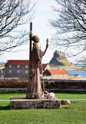 Statue of St. Aidan with Lindisfarne Castle in the background
